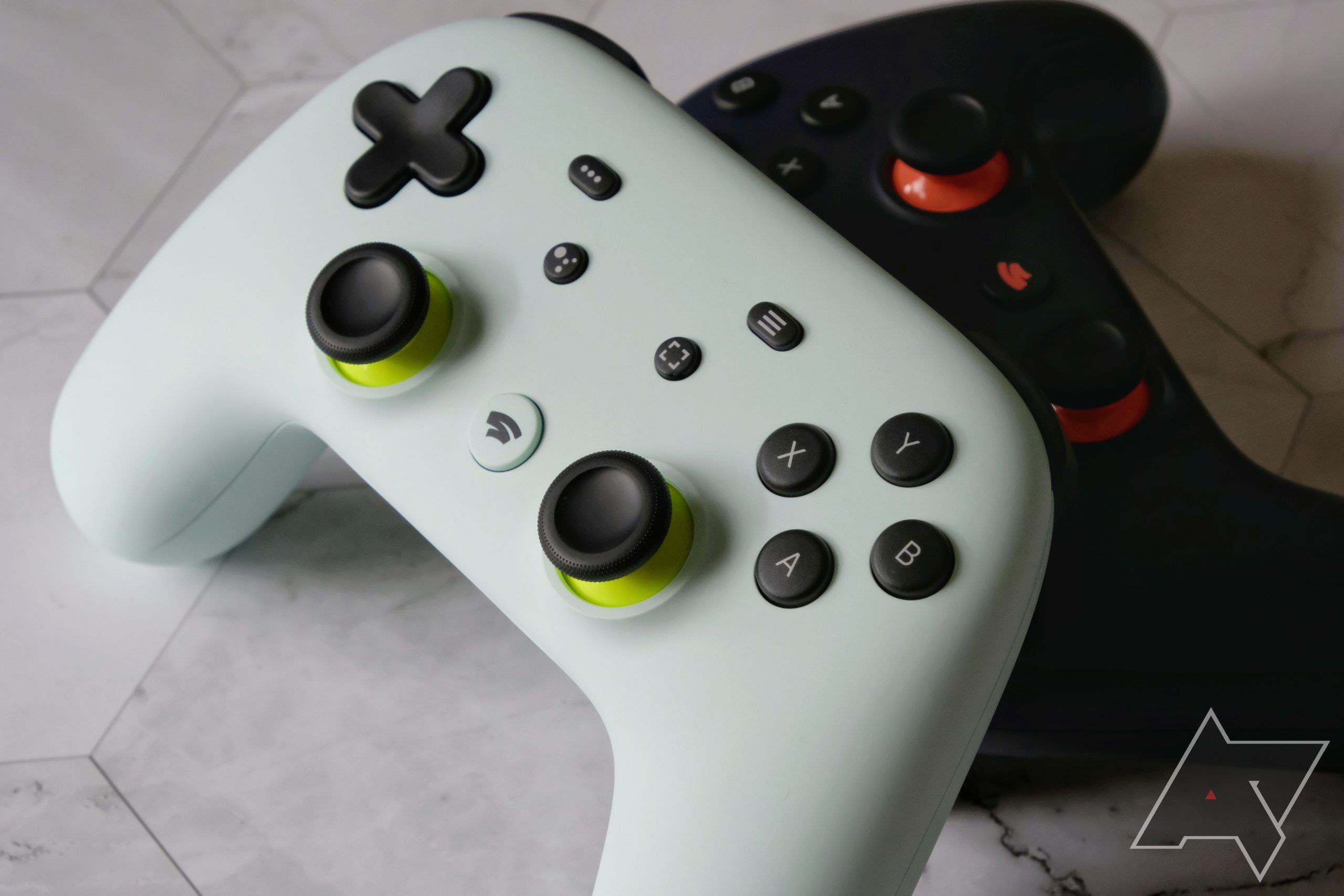 Un contrôleur Stadia Wasabi Green et Night Blue sur fond de tuile